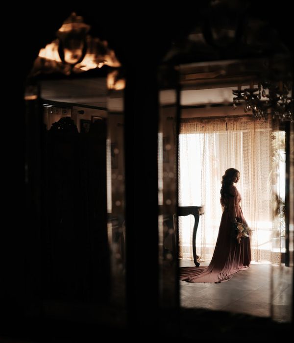 Woman in a serene yoga pose in a dark room with cyan light highlights.